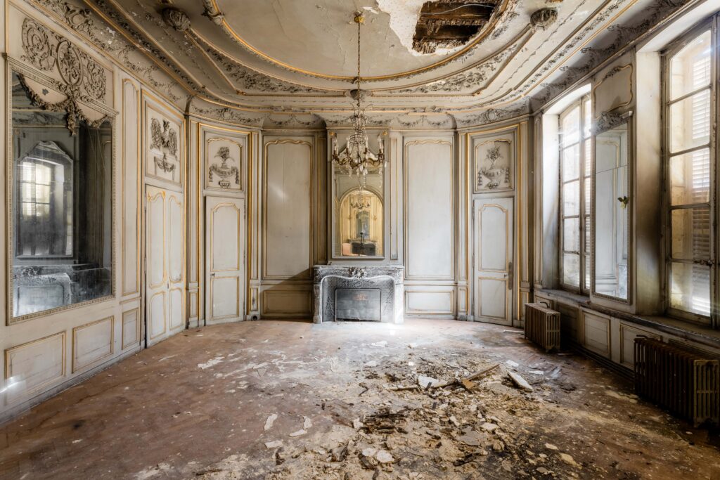 Salon abandonné avec des moulures et un plafond décoratif en ruine